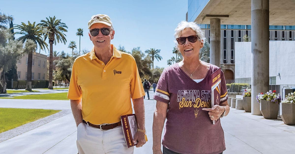 Two residents decked out in Sun Devils gear take a relaxed walk outdoors.